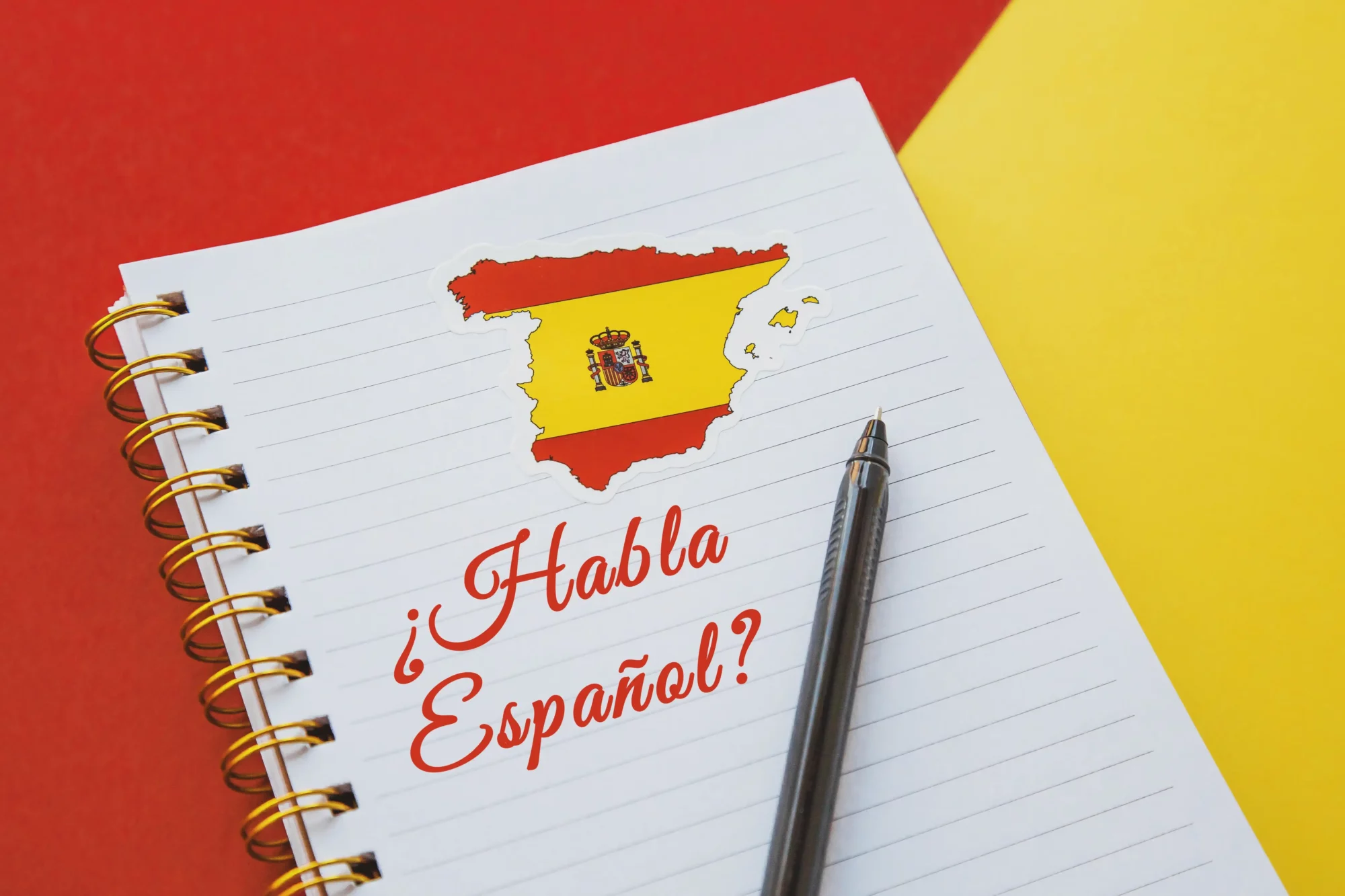 A notebook with a map of Spain and an inscription “¿Habla español?” with a pen on top