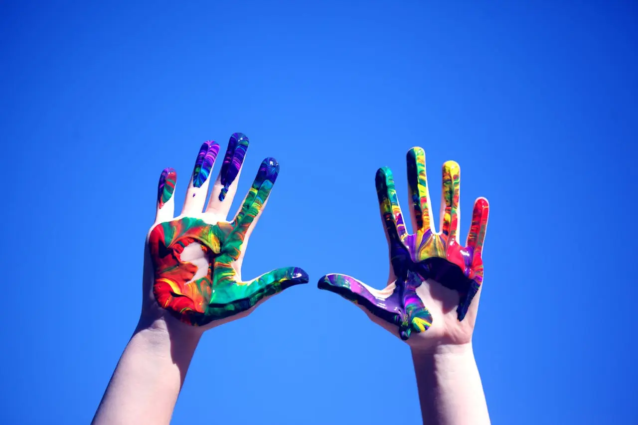 hands covered with multicolored paint